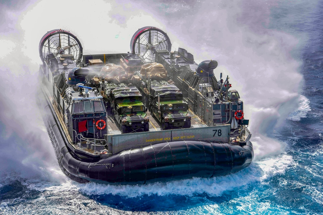 An air-cushioned landing craft splashes in the water.