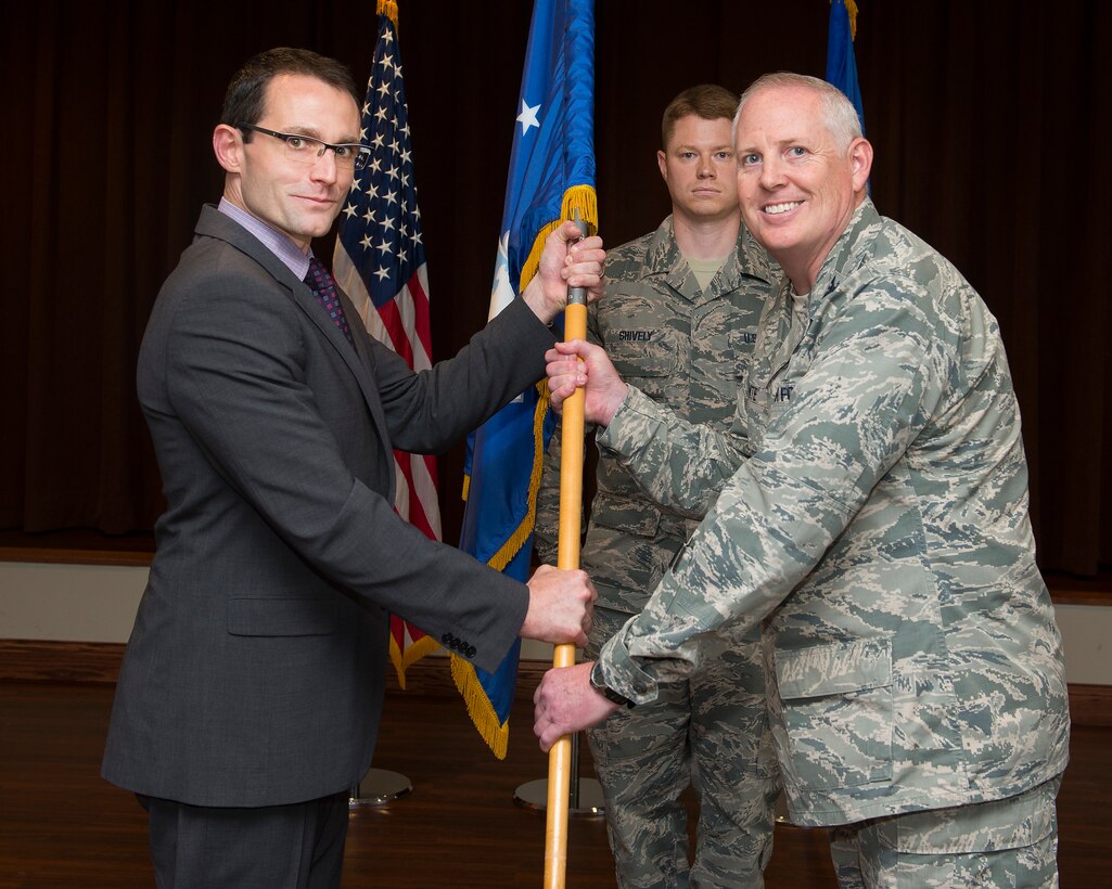 Col. Dale White accepts the guidon from Dr. William Roper, Assistant Secretary of the Air Force for Acquisition, Technology and Logistics, July 26, 2018, as he assumes leadership of the Air Force Life Cycle Management Center’s Intelligence, Surveillance, Reconnaissance and Special Operations Forces Directorate during a ceremony in the Wright-Patterson Air Force Base, Ohio club, as Senior Master Sgt. Michael J. Shively looks on. (U.S. Air Force photo by R.J. Oriez)