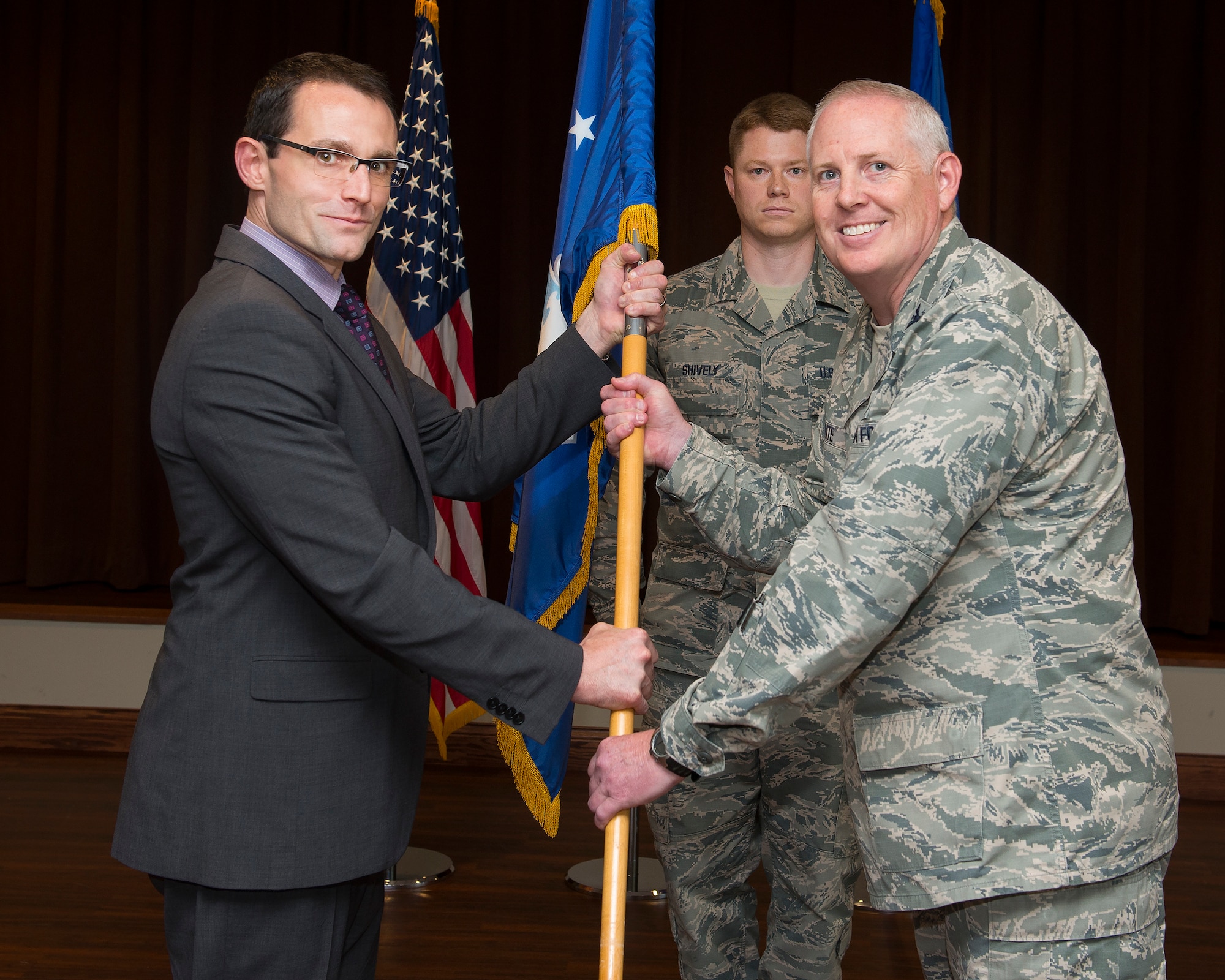 Col. Dale White accepts the guidon from Dr. William Roper, Assistant Secretary of the Air Force for Acquisition, Technology and Logistics, July 26, 2018, as he assumes leadership of the Air Force Life Cycle Management Center’s Intelligence, Surveillance, Reconnaissance and Special Operations Forces Directorate during a ceremony in the Wright-Patterson Air Force Base, Ohio club, as Senior Master Sgt. Michael J. Shively looks on. (U.S. Air Force photo by R.J. Oriez)