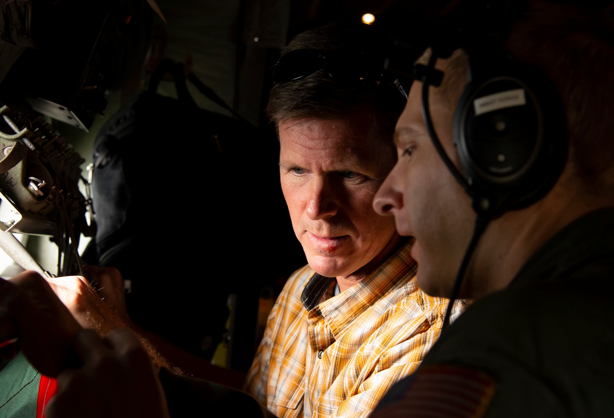 Richard Burchfield, Colorado Springs Chamber and Economic Development Council, listens as Chief Master Sgt. Joseph Rorick, the 302nd Operations Group superintendent and loadmaster, explains his mission while flying in a C-130 Hercules aircraft during the 302nd Airlift Wing Partners in Leadership program July 20, 2018.