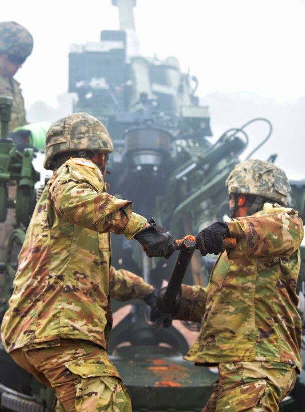 Guard soldiers load the 155 mm round into the M777A2 towed 155 mm howitzers.