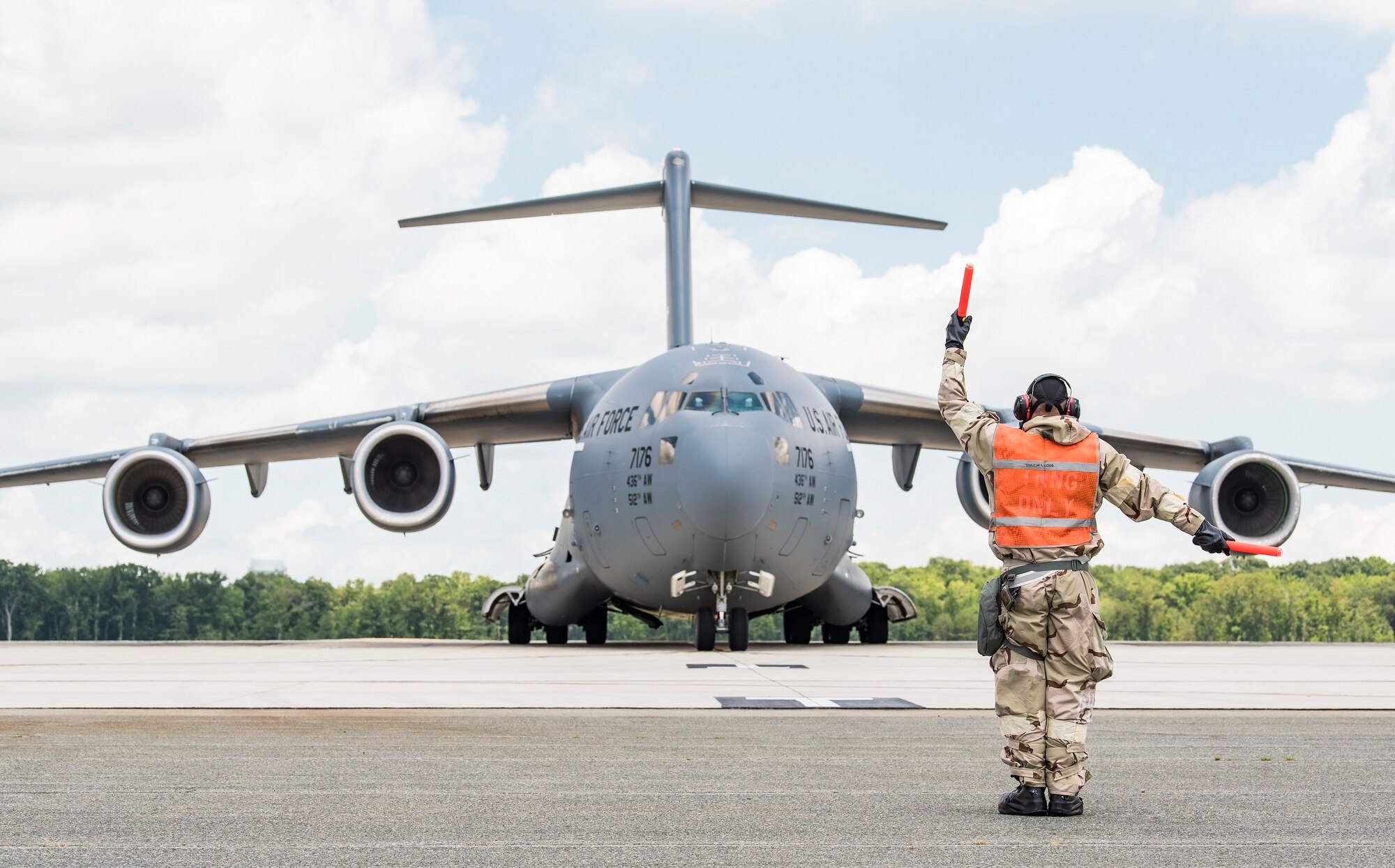 Senior Airman Christopher Leigh, 736th Aircraft Maintenance Squadron crew chief, marshals a C-17 Globemaster III during exercise Vengeant Eagle 2.0 on July 26, 2018, at Dover Air Force Base, Del. During the exercise, personnel were evaluated on their ability to perform normal flight line operations in simulated chemical, biological, radiological and nuclear environments and various force protection conditions. (U.S. Air Force photo by Roland Balik)