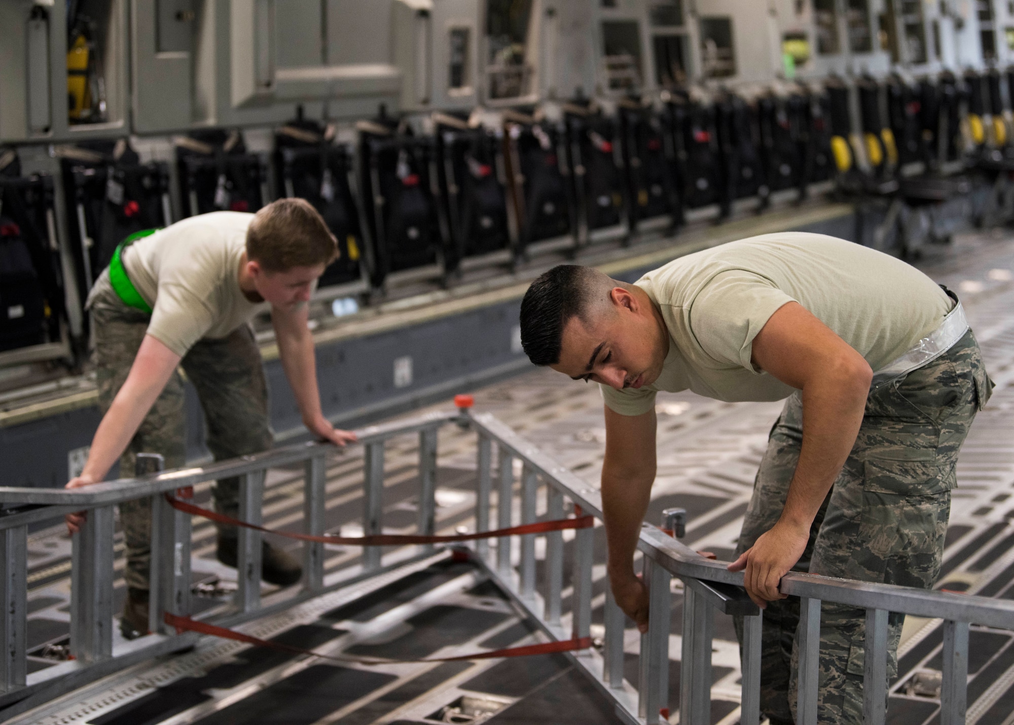 U.S. Air Force Staff Sgt. Caleb Langel, a 517th Aircraft Maintenance Unit C-17 Globemaster III dedicated crew chief, folds up a ladder with Senior Airmen Melanie Hansen, a 517th AMU aerospace maintenance journeyman, during an inspection at Joint Base Elmendorf-Richardson, Alaska, July 26, 2018. Langel and Hansen are responsible for service and repair on everything coming back from daily inspections, to include checking the pressure gauges on life rafts to ensure they meet specifications to fully inflate if needed.