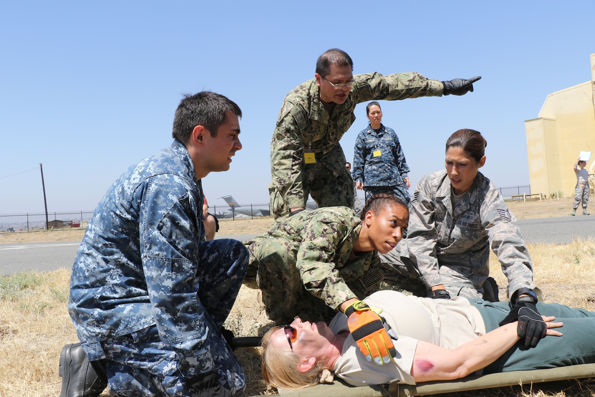 U.S. Navy Hospital Corpsman Asia Rankin, Emergency Medical Force Detachment D, Camp Pendleton, secures a simulated patient for transport while U.S. Navy Petty Officer 2nd Class Christopher Burgoa, EMF Det. B, Camp Pendleton, directs the team toward a simulated Battalion Aid Station here June 23, 2018.