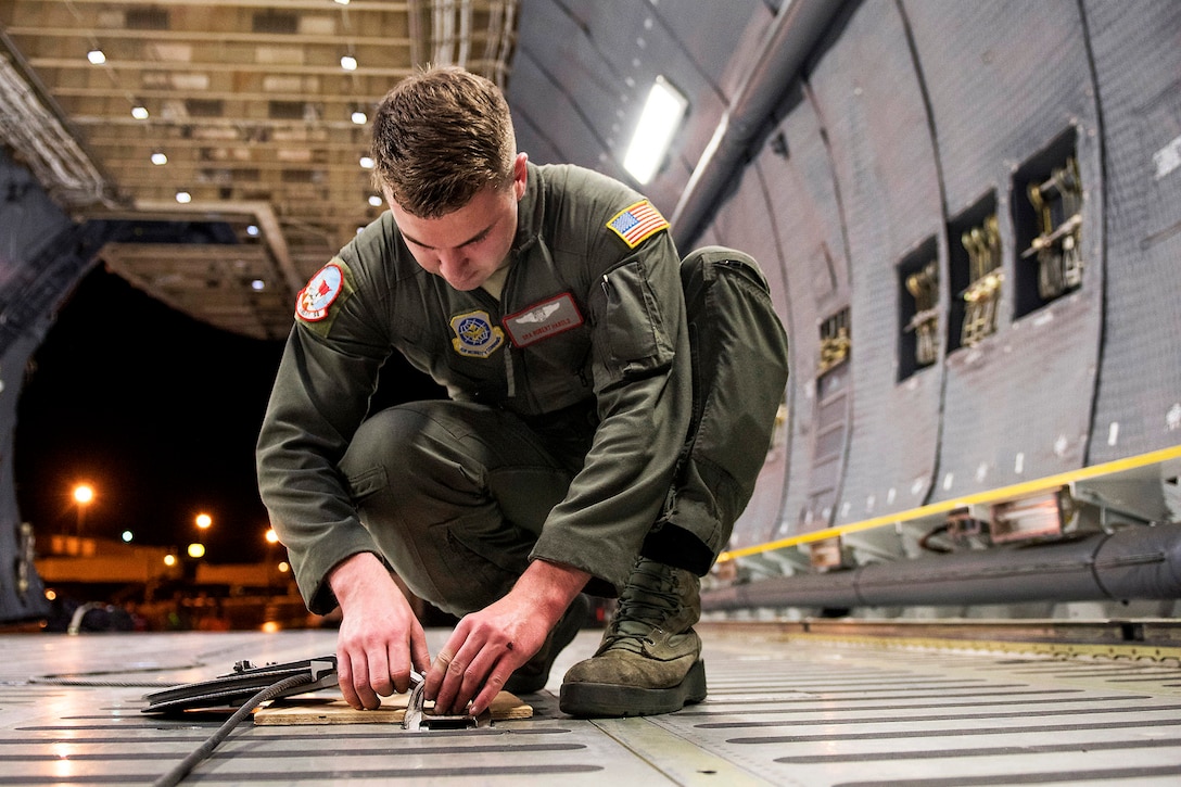 An airman secures a pulley on a C-5M Super Galaxy.