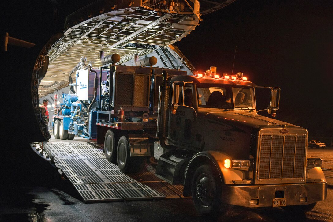 Airmen unload a double recirculating cement mixer trailer.