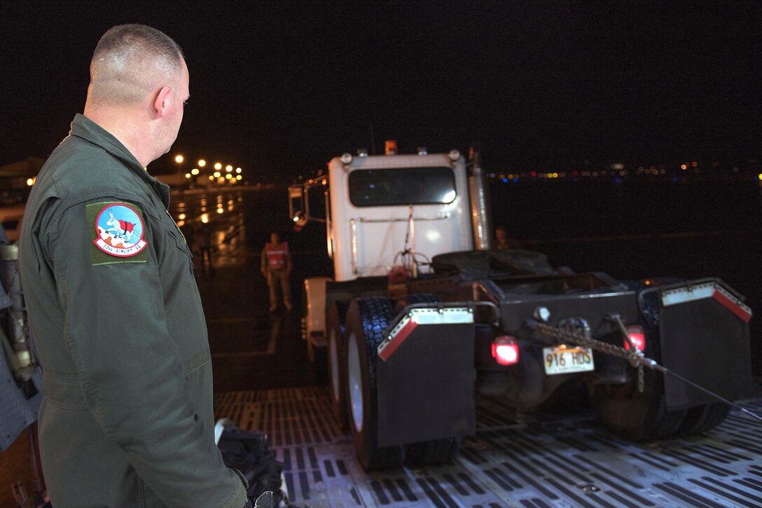 An airman guides a truck onto a C-5M Super Galaxy.