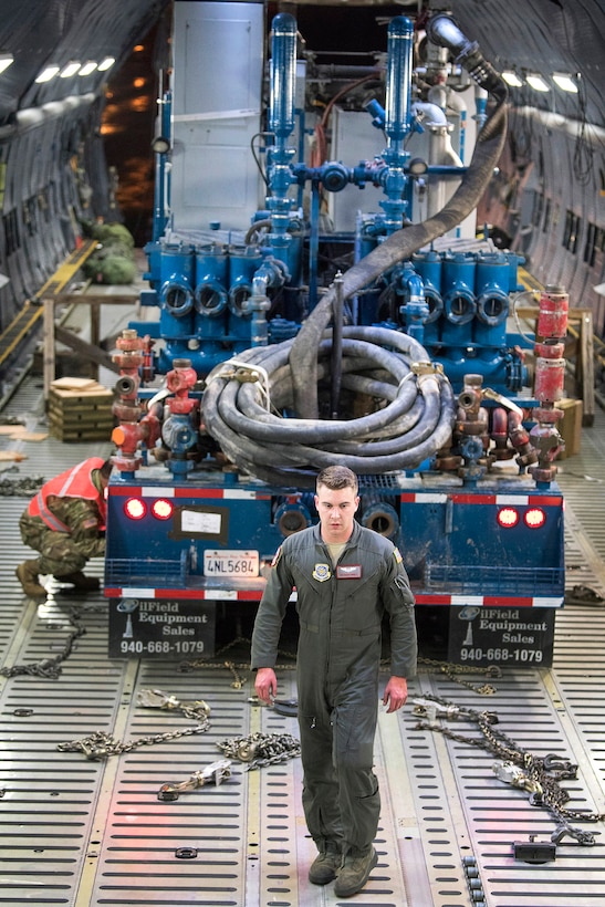 An airman helps unload a double recirculating cement mixer trailer.