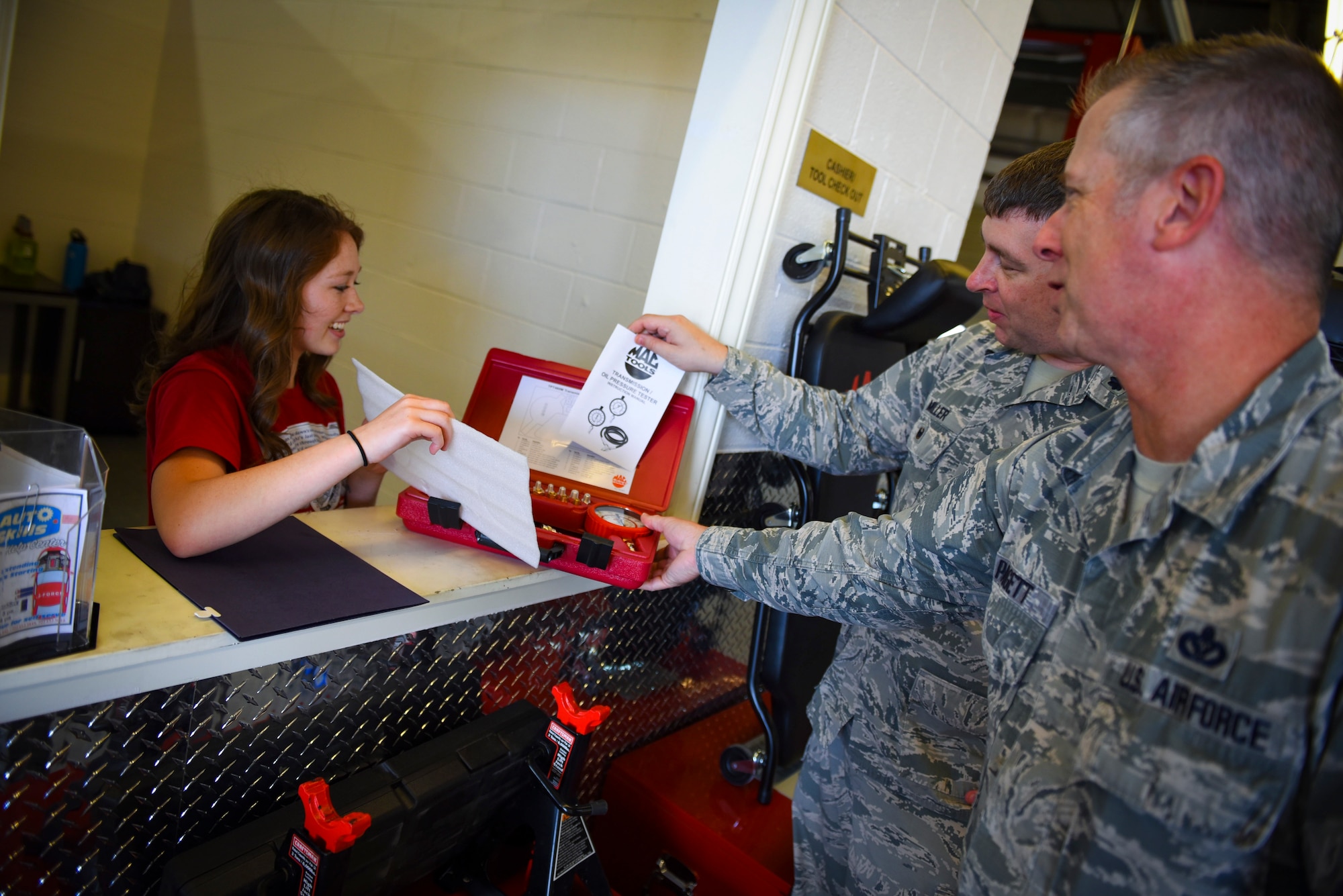 Kearsten Drown, 99th Force Support Squadron Auto Hobby Shop cashier, hands a set of gauges to Lt. Col. Paul Miller, 99th Mission Support Group deputy commander, and Chief Master Sgt. Rob Padgett, 99 MSG superintendent, at Nellis Air Force Base, Nevada, May 31, 2018. The renovations included purchasing new tools and equipment that customers can check out as well as a complete makeover inside the shop to provide a cleaner, climate-controlled area. (U.S. Air Force photo by Airman 1st Class Andrew D. Sarver)