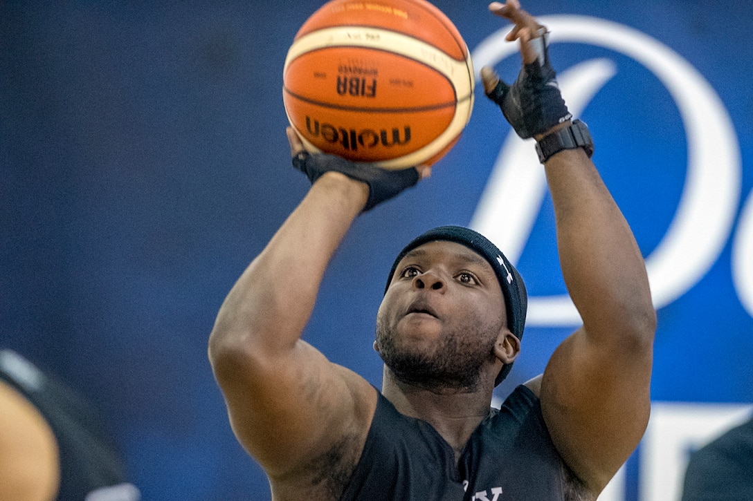 A soldier holds a basketball over his head to take a shot.