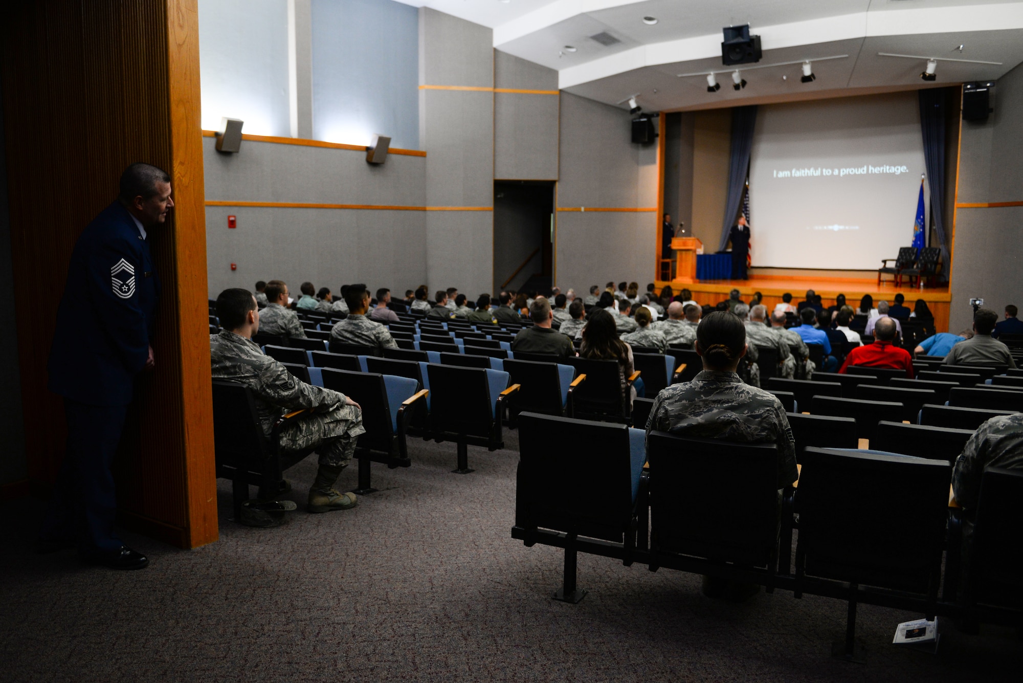 Chief Master Sgt. Allan Turk, 47th Operations Support Squadron radar approach control chief controller, takes a sneak peak of the opening slideshow for his retirement ceremony at Laughlin Air Force Base, Texas, June 1, 2018. Just moments before the official party was introduced to the ceremony, Turk couldn’t resist watching the retirement video put together for him on the big screen. (U.S. Air Force photo by Senior Airman Benjamin N. Valmoja)