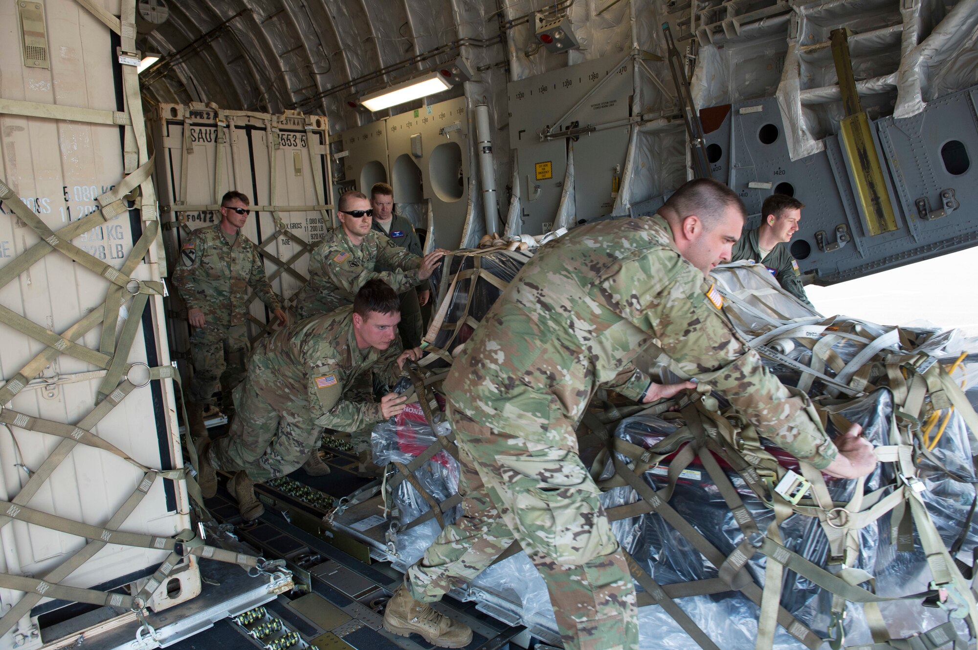 Army Soldiers from the 555th Engineer Brigade and Air Force Airmen from the 4th Airlift Squadron work together to unload a pallet of equipment from a C-17 Globemaster III, May 21, 2018, at Moses Lake, Wash. The Soldiers were moving vehicles and equipment from Joint Base Lewis-McChord to Moses Lake part of a rapid deployment exercise. (U.S. Air Force photo by A1C Sara Hoerichs)