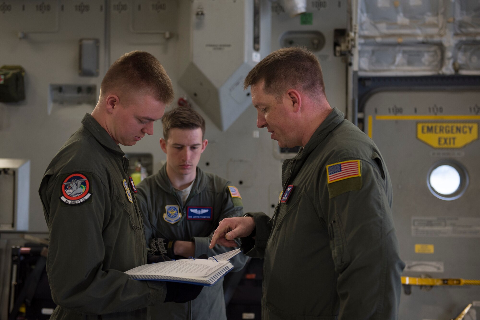 From Left, Airman 1st Class Alexander Donaldson, Senior Airman Justin Thompson and Tech Sgt. Brian Layton, 4th Airlift Squadron loadmasters review a checklist May 21, 2018, at Joint Base Lewis-McChord, Wash. Loadmasters are responsible for everything that goes on in the cargo compartment of the aircraft from loading and securing cargo to ensuring passengers have what they need during flight. (U.S. Air Force photo by A1C Sara Hoerichs)
