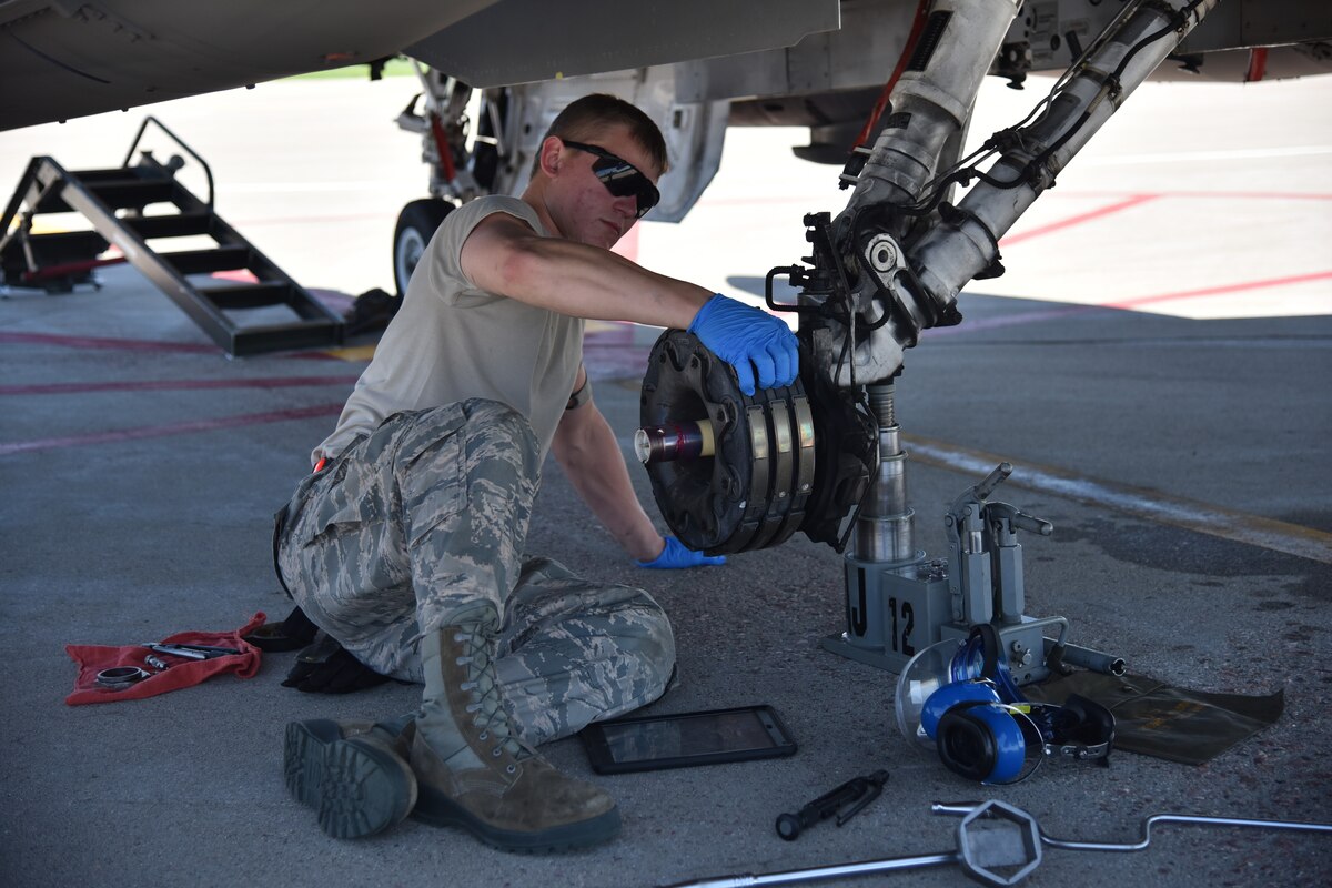 Airman inspects breaks on F-16 aircraft before installing new tire