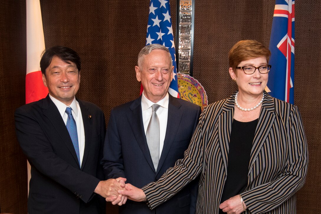 Three defense leaders pose for a photograph with their hands together.