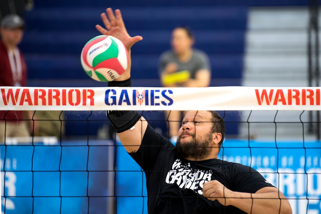 A soldier spikes a ball during sitting volleyball practice.