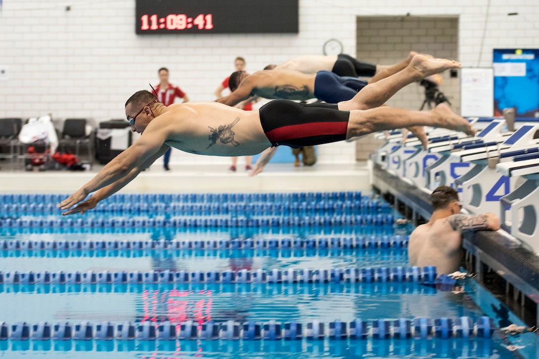 Marines train on the starting block during swimming practice.