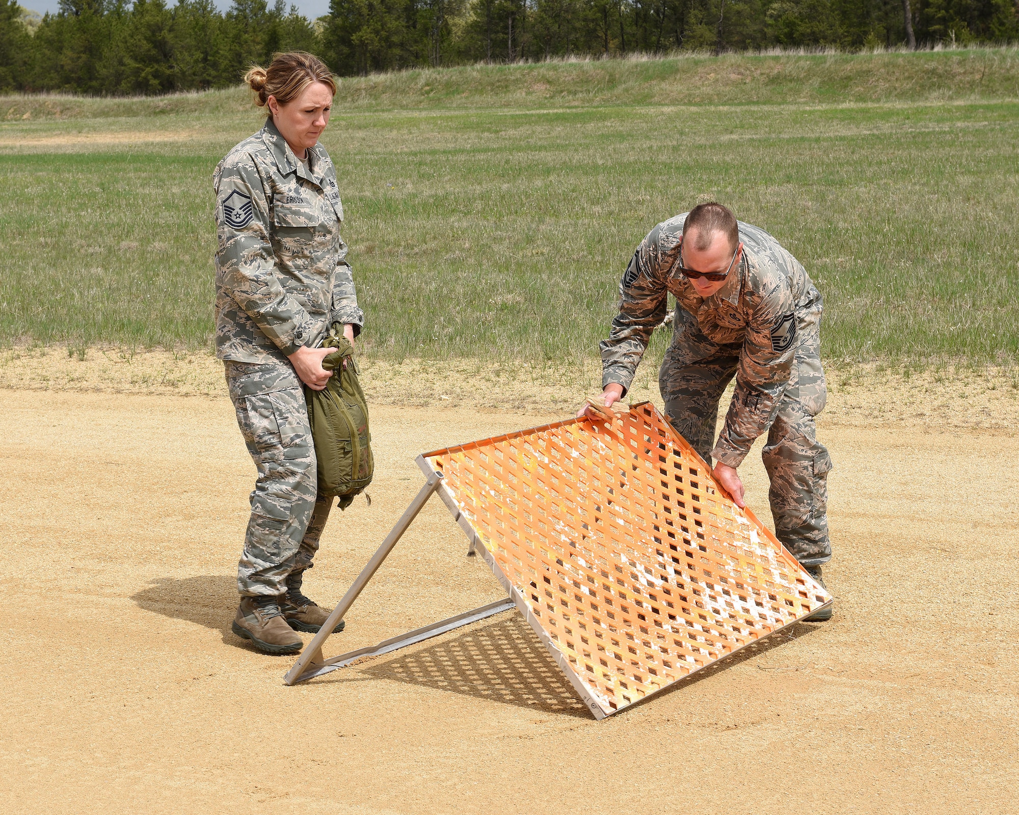 U.S. Air Force Master Sgt. Christina Ericson, left, and Senior Master Sgt. Brent Bixby, airfireld management specialists from the 182nd Airlift Wing, Illinois Air National Guard, establish the touchdown zone by placing orange assault panels along the edges of the dirt runway at Young Landing Zone located at Fort McCoy, Wis. May 14, 2018. A number of pilots were qualifying to complete their unimproved landing certification. (U.S. Air National Guard photo by Master Sgt. Todd A. Pendleton)