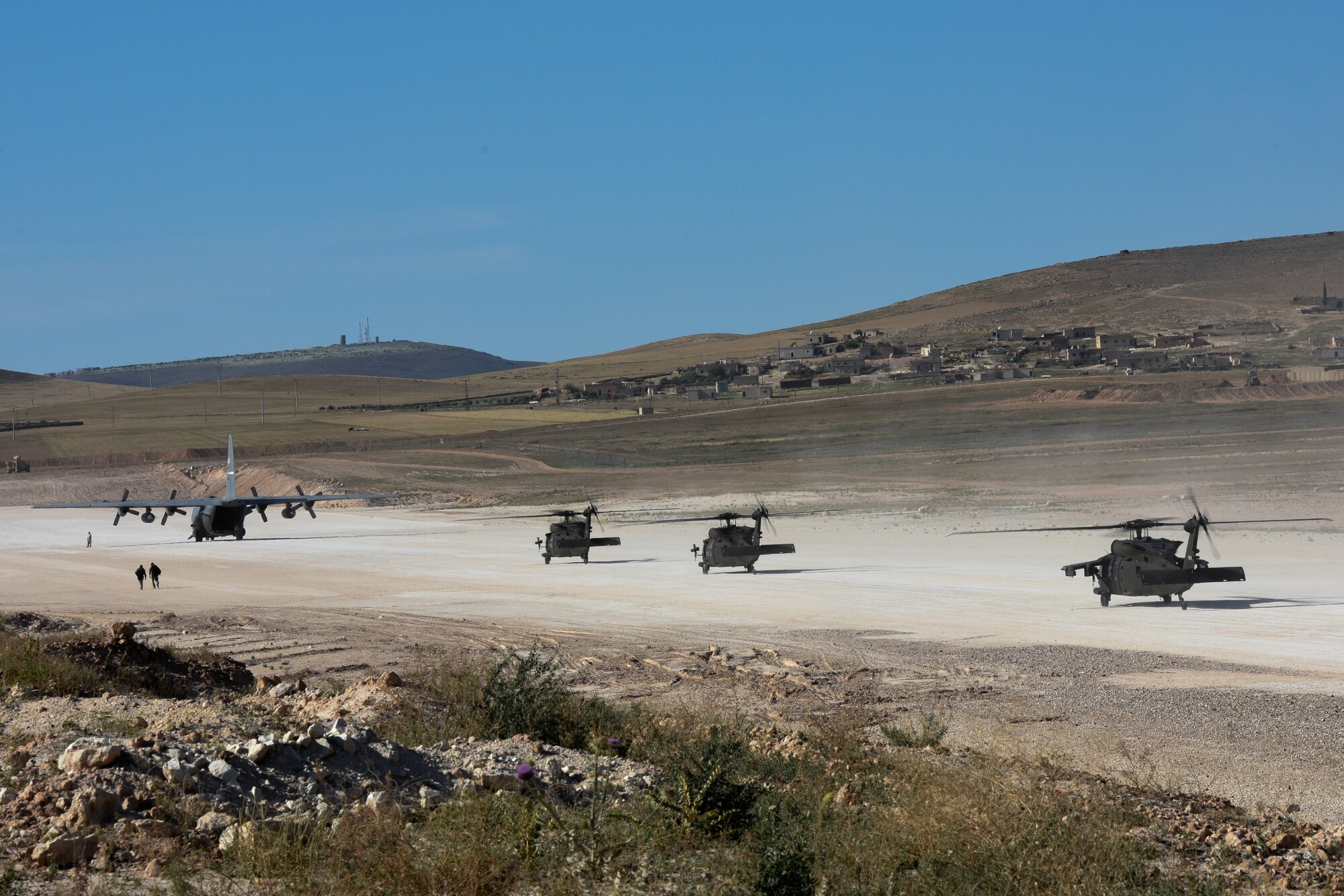 A U.S. Air Force C-130H Hercules and U.S. Army UH-60 Blackhawks sit on a landing zone at an undisclosed location, May 17, 2018. All types of aircraft fly in and out of the landing zone in support of Operation Inherent Resolve. (U.S. Air Force photo by Tech. Sgt. Caleb Pierce)