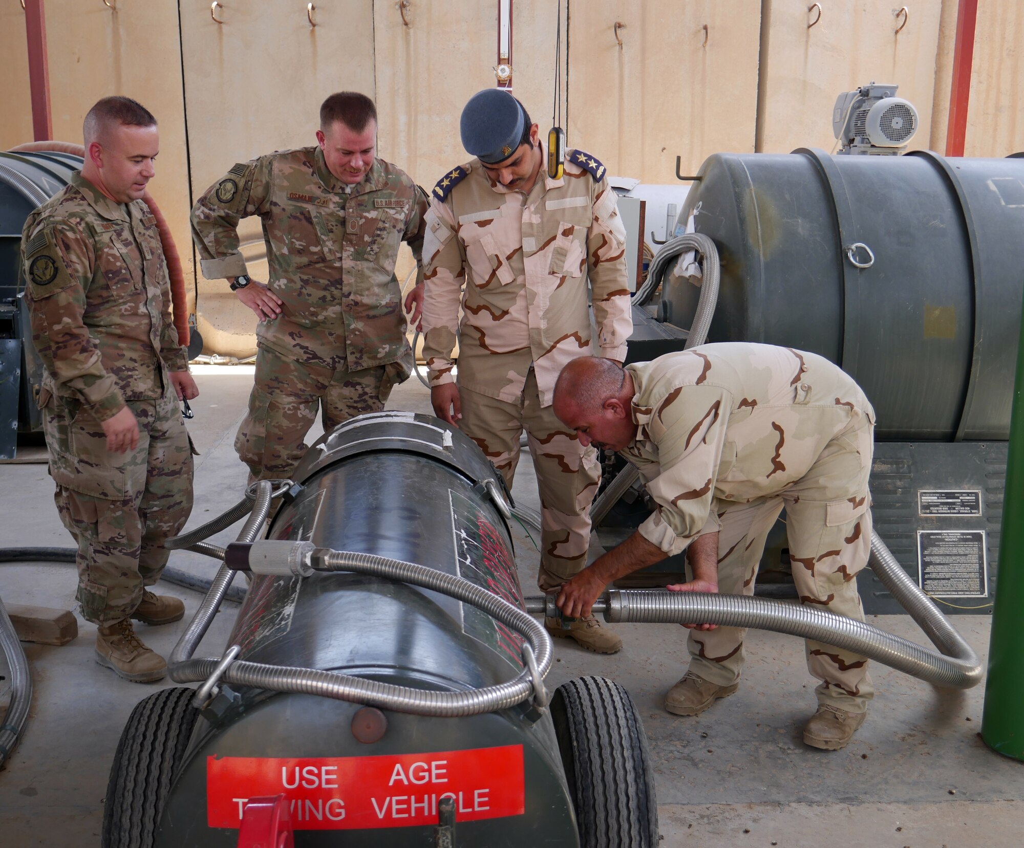 (L-R) Senior Master Sgt. Tim Smith and Master Sgt. Brian Osman, air advisors assigned to the 770th Air Expeditionary Advisory Squadron, and Iraqi Air Force 1st Lt. Alaa Aziz, oxygen officer, watch an Iraqi maintenance airman fill up a tank with liquid oxygen May 22, 2018, at Al Muthana Air Base in Baghdad, Iraq. (U.S. Air Force photo by Capt. Benjamin Hughes)