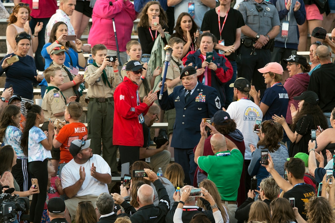 Air Force Senior Master Sgt. Israel Del Toro carries the torch into Falcon Stadium during the open ceremonies for the 2018 Defense Department Warrior Games.