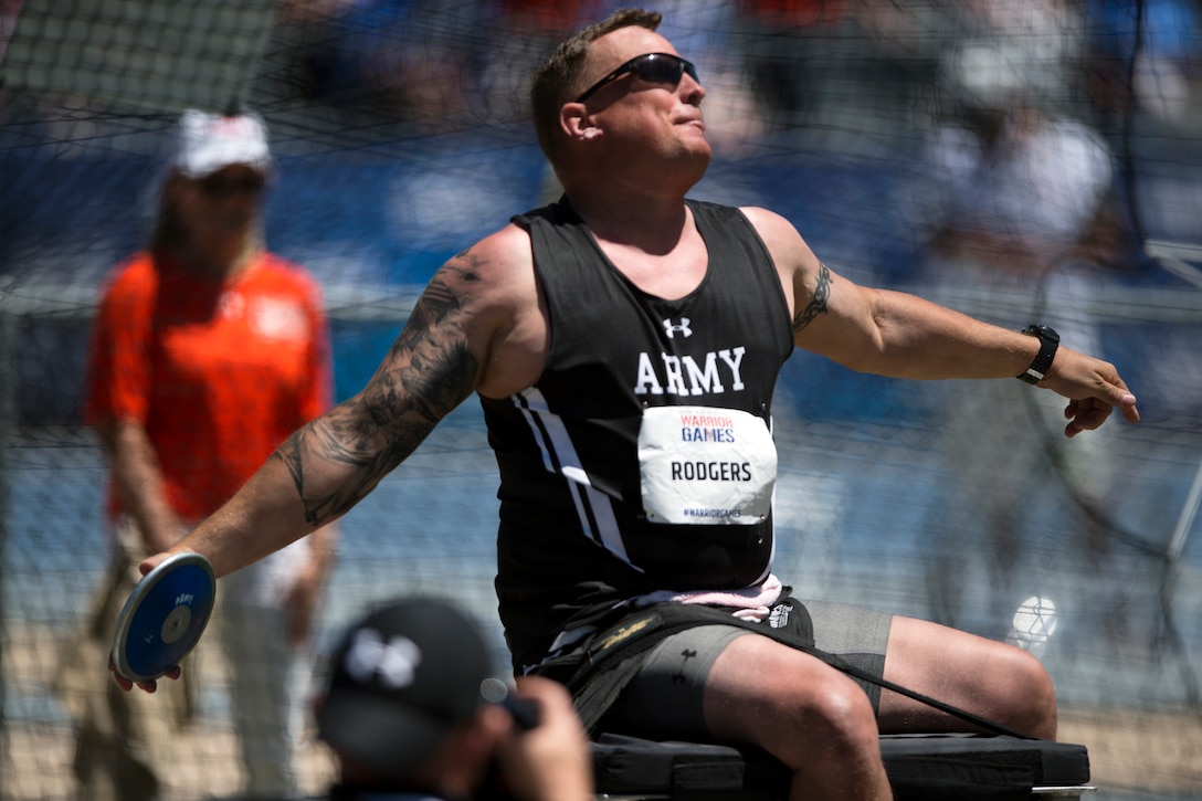 A service member competes in the seated discus competition.