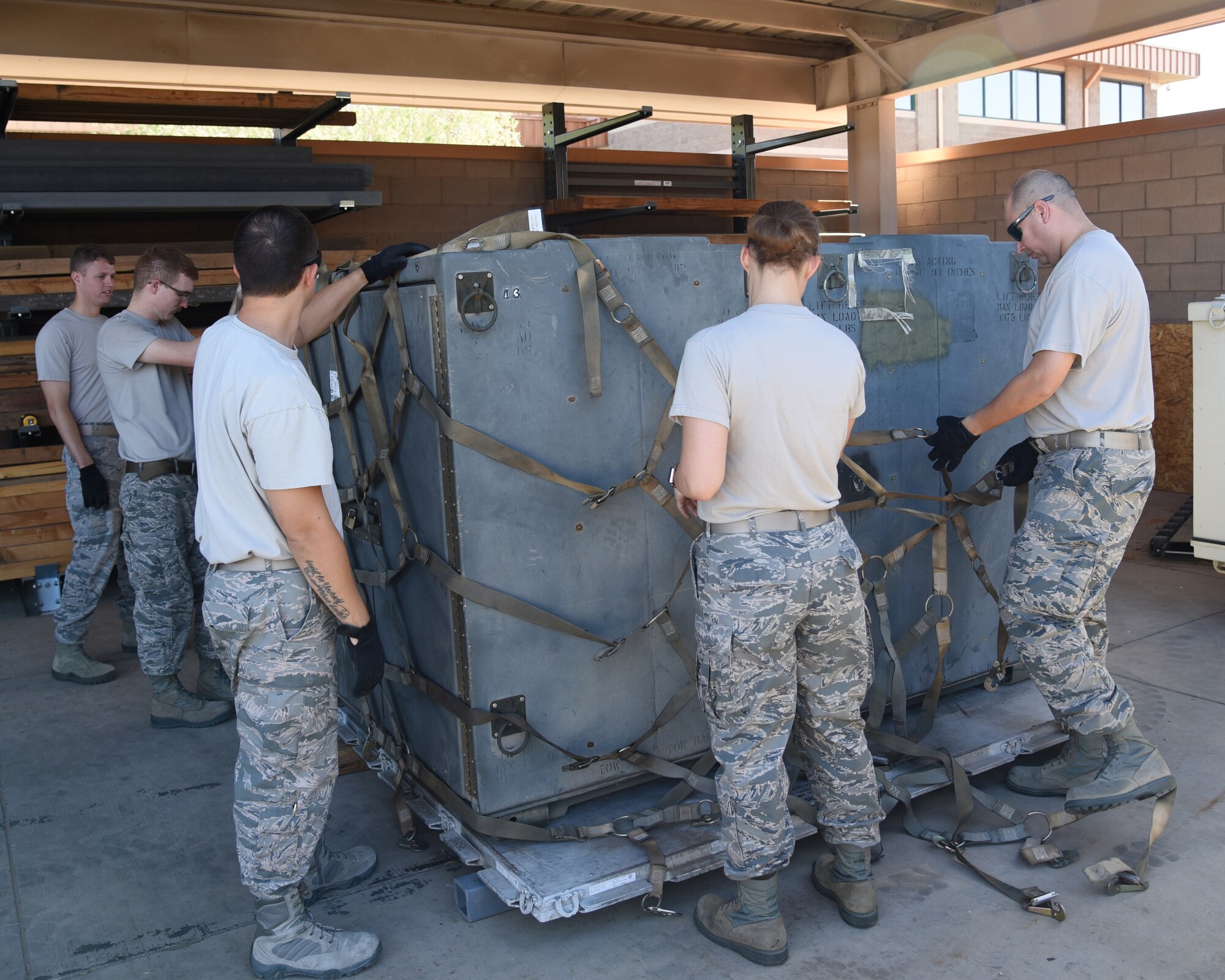 Airmen from the 161st Air Refueling Wing secure a shipping container onto a pallet during a cargo pallet preparation class at Goldwater Air National Guard Base, June 3, 2018. Working as a team insures that the load is properly secured for transportation and that all safety precautions have been made prior to transporting the cargo.  (U.S. Air National Guard photo by Staff Sgt. Wes Parrell)