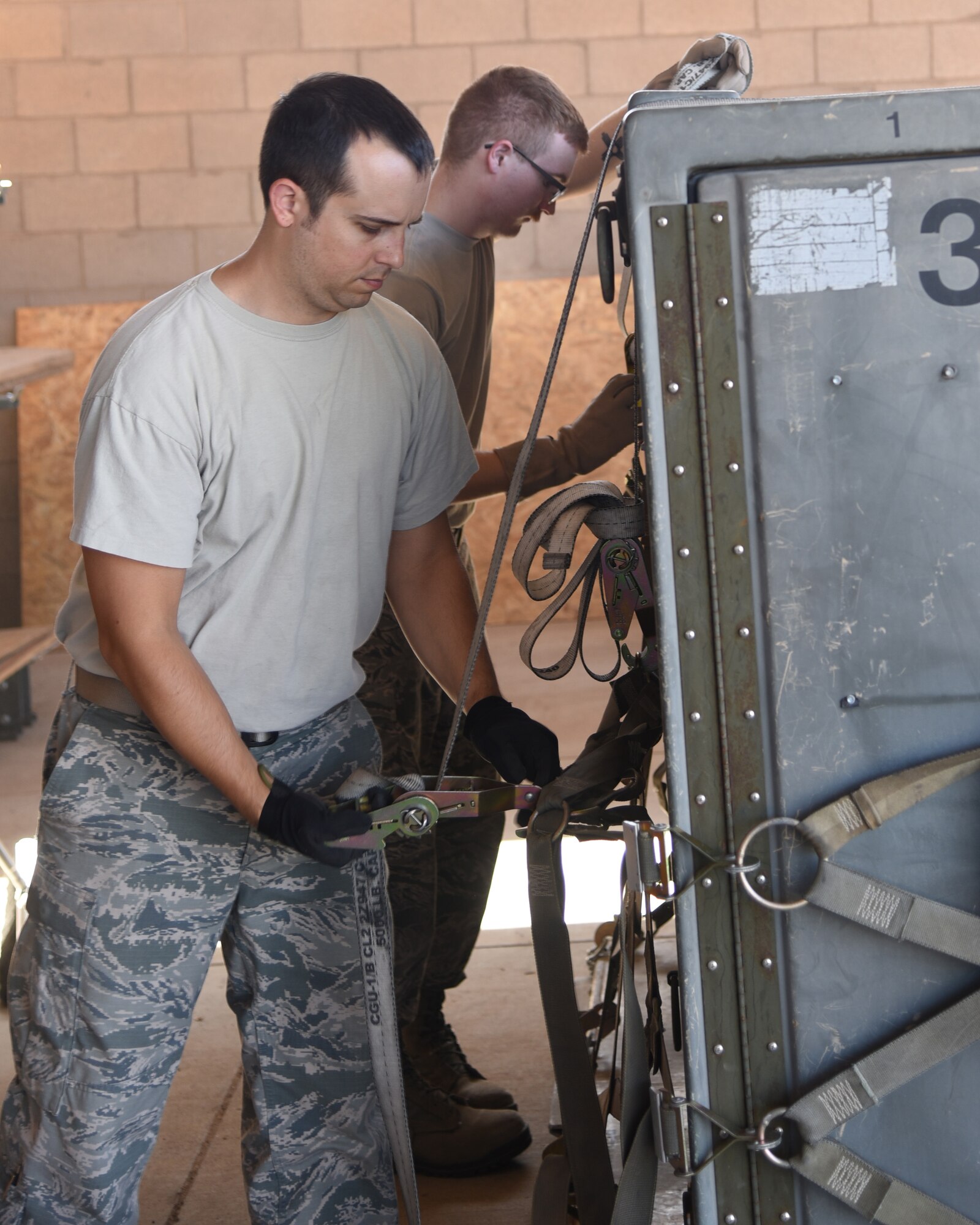 Staff Sgt. Zachary Milne and Staff Sgt. Joshua, aircrew flight equipment technicians with the 161st Air Refueling Wing, secure cargo netting to a pallet during a cargo pallet preparation class at Goldwater Air National Guard Base, June 3, 2018. Properly securing cargo netting and load straps insure that cargo does not shift while being transported. (U.S. Air National Guard photo by Staff Sgt. Wes Parrell)