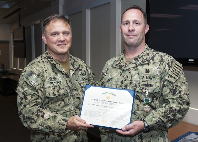 Naval Surface Warfare Center Panama City Division (NSWC PCD)Commanding Officer Capt. Aaron Peters, USN, left, congratulates Navy Diver Chief (DSW/EXW/SW) Taylor Arney, USN, right, on receiving the Navy and Marine Corps Commendation Medal for his meritorious service while serving as research, development, testing, and evaluation diving operations chief and assistant production officer at NSWC PCD. U.S. Navy photo by Eddie Green