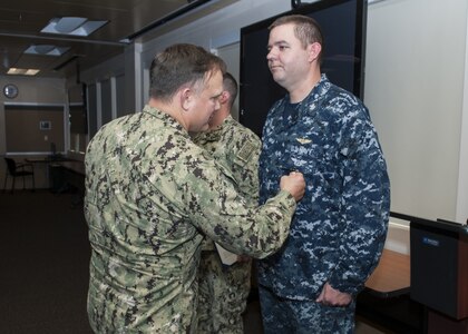 Naval Surface Warfare Center Panama City Division (NSWC PCD)Commanding Officer Capt. Aaron Peters, USN, left, frocks Naval Aircrewman 1st Class (NAC/AW) Martin Long, USN, right, with the Navy and Marine Corps Achievement Medal for his professional achievement as operations leading petty officer at NSWC PCD. U.S. Navy photo by Eddie Green