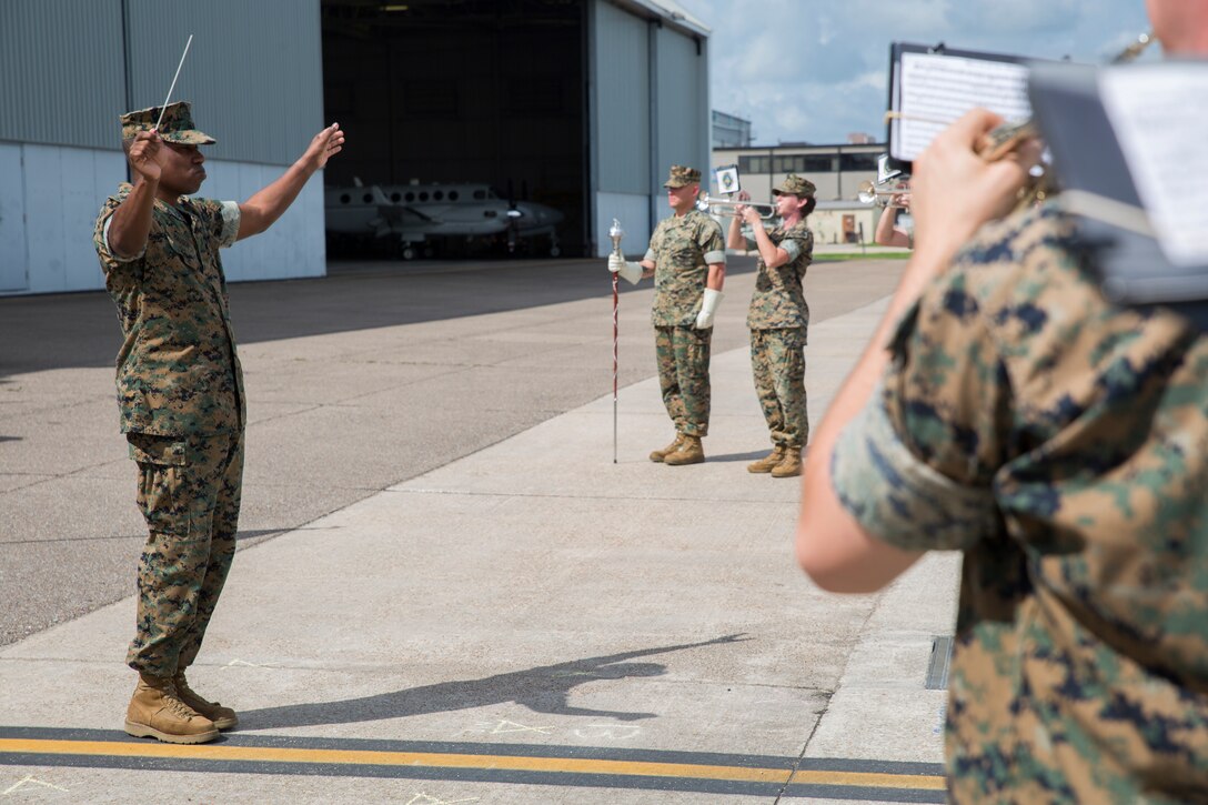 Gunnery Sgt. Justin Hauser, band master with the Marine Forces Reserve Band, conducts the band prior to the start of the 4th Marine Aircraft Wing sergeant major relief and appointment ceremony at the Marine Light Attack Helicopter Squadron 773, Marine Aircraft Group 49, 4th MAW, flight line, New Orleans, June 2, 2018. Sgt. Maj. Rodney L. Lane, sergeant major of 4th MAW, relinquished his duties to Sgt. Maj. Thomas M. Burkhardt. (U.S. Marine Corps photo by Sgt. Melissa Martens)