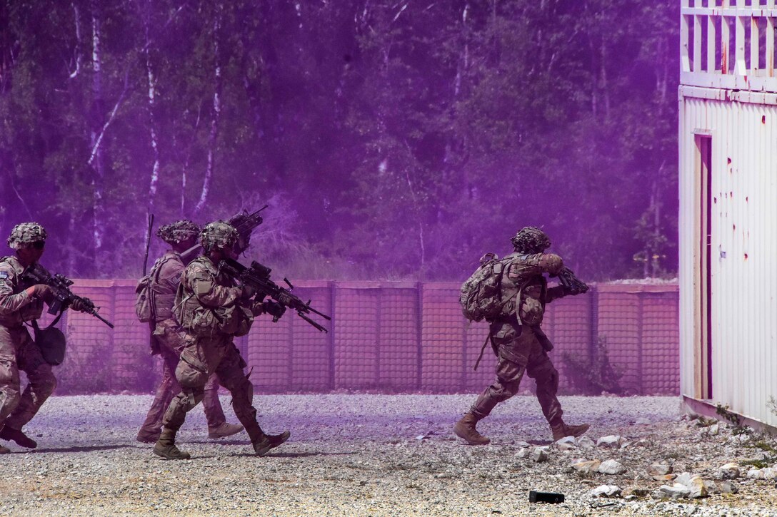 Soldier maneuver through the cover of smoke before entering a building.