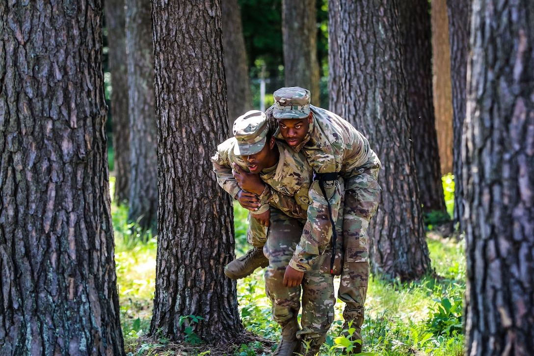 A soldier carries another soldier during combat lifesaver training.