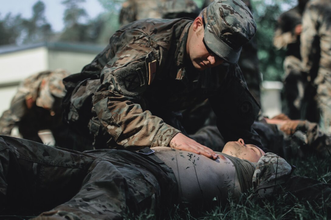 A soldier checks the breathing of another soldier.