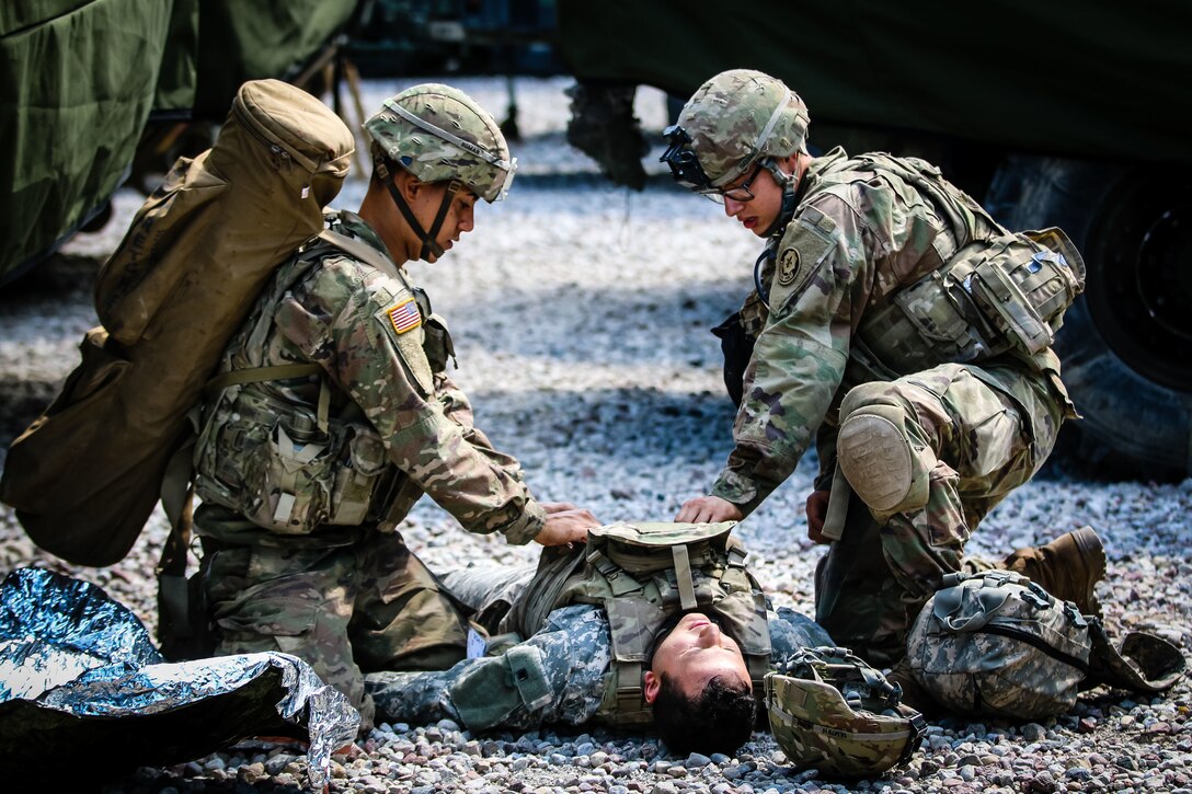 A soldier provides combat casualty care to another soldier.