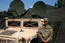 Soldier standing in front of satellite terminal