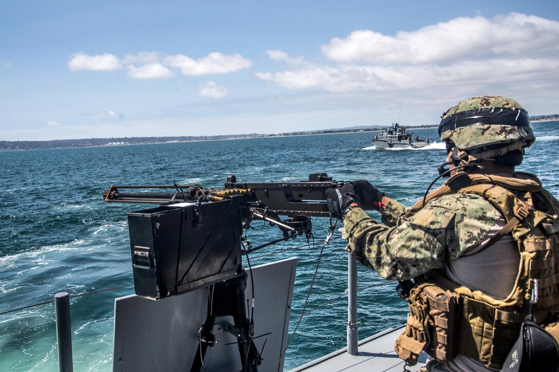 A sailor prepares to fire a .50-caliber machine gun.