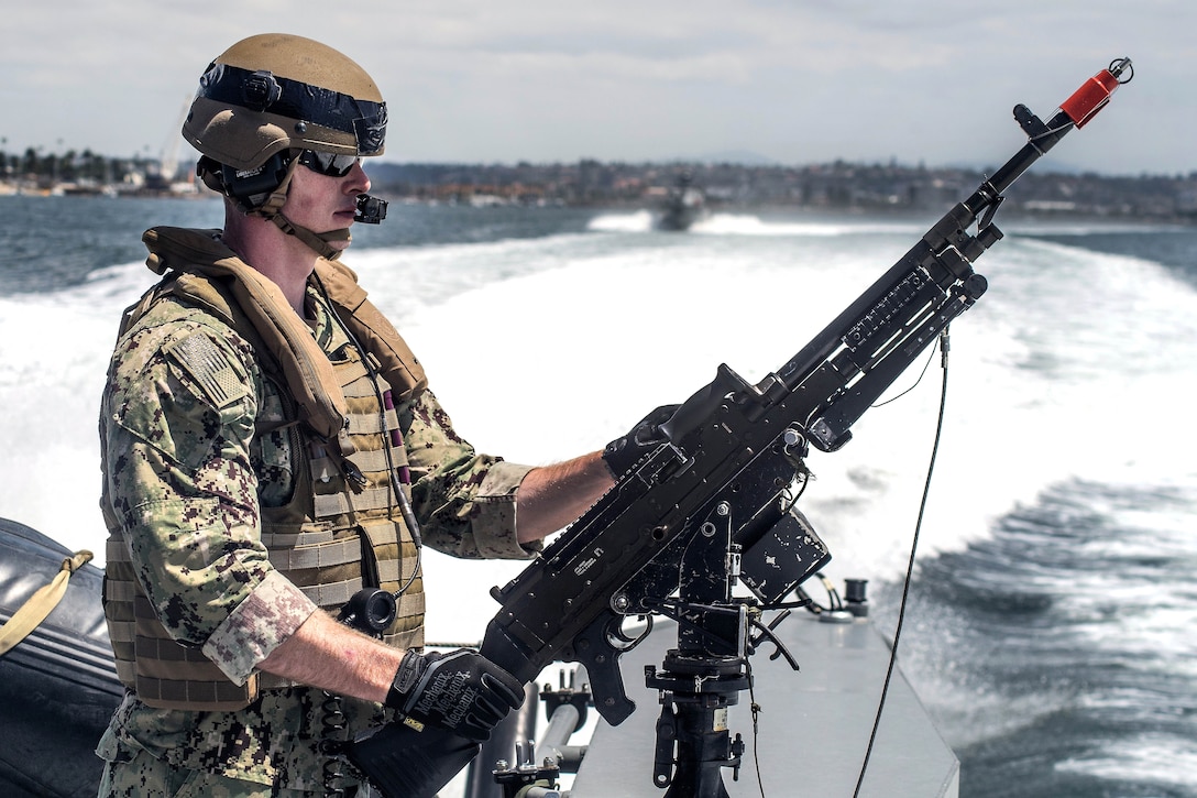 A sailor provides security while manning an M240 caliber machine gun.