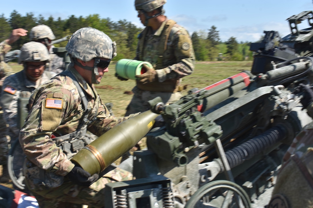 A soldier prepares to load a 155 mm artillery round into an M777 howitzer.