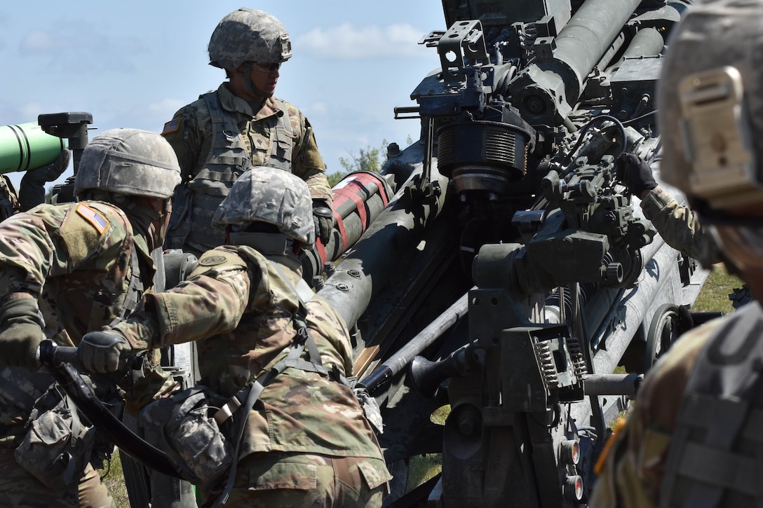 Soldiers load a 155 mm artillery round into an M777 howitzer.