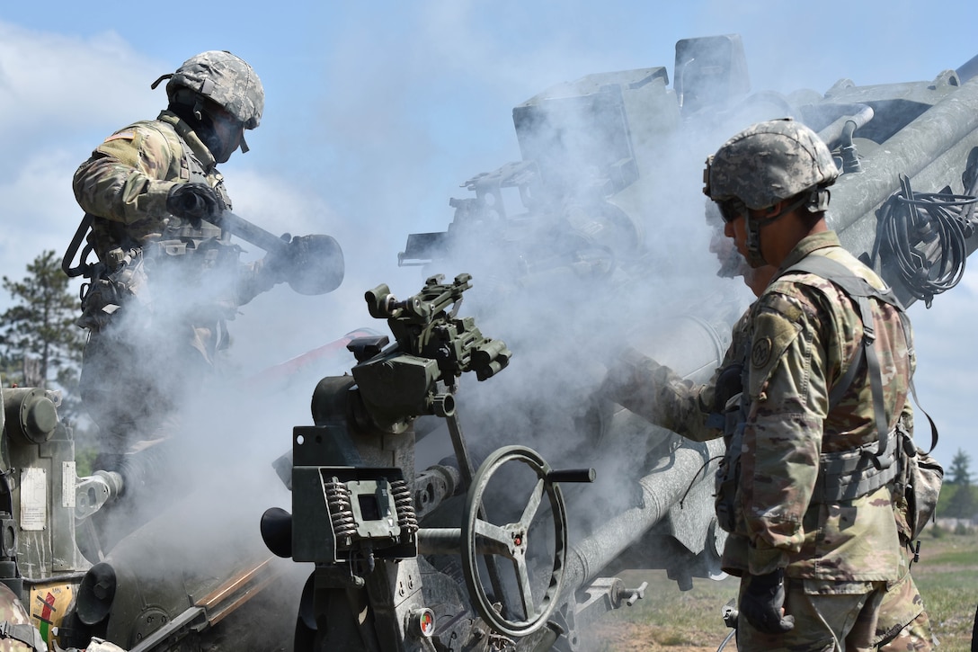 Soldiers clear a 155 mm artillery round from a M777 howitzer.