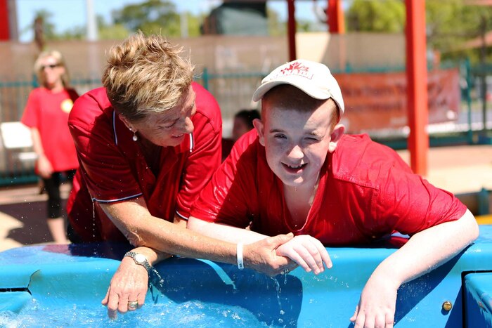 A woman and a special needs child interact while engaged in playing with a stream of water.