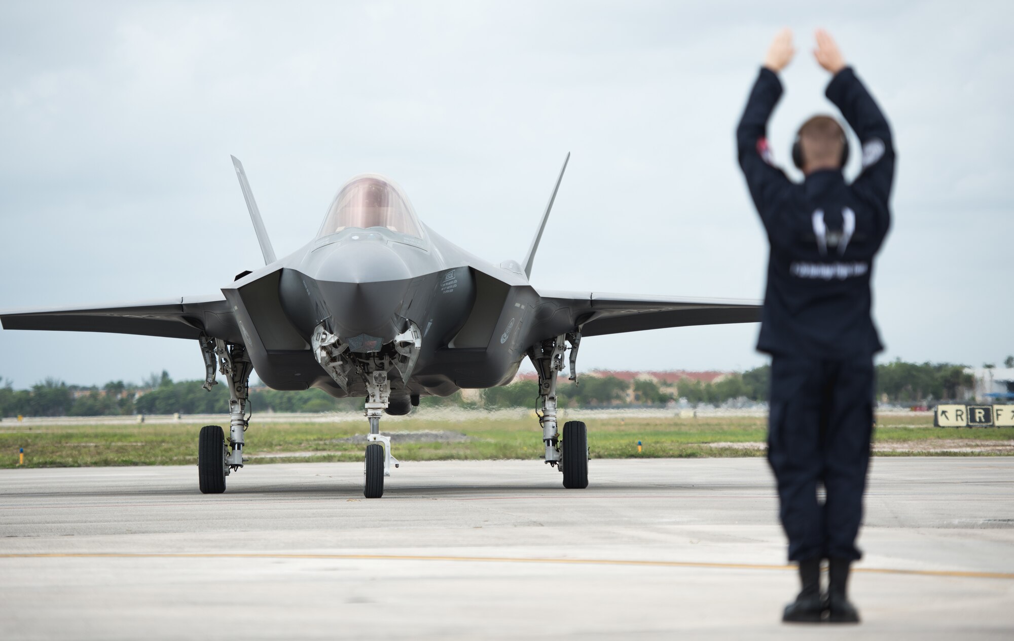 Staff Sgt. Michael Couture, F-35 Heritage Flight Team crew chief, marshals an F-35A Lightning II upon arrival at the Miami-Opa Locka Executive Airport in Opa-Locka, Fla., May 24, 2018. The F-35 HFT arrived in Miami to perform at the 2018 Hyundai Air and Sea show; a two-day event held during Memorial Day weekend to honor military service members. (U.S. Air Force photo by Airman 1st Class Alexander Cook)