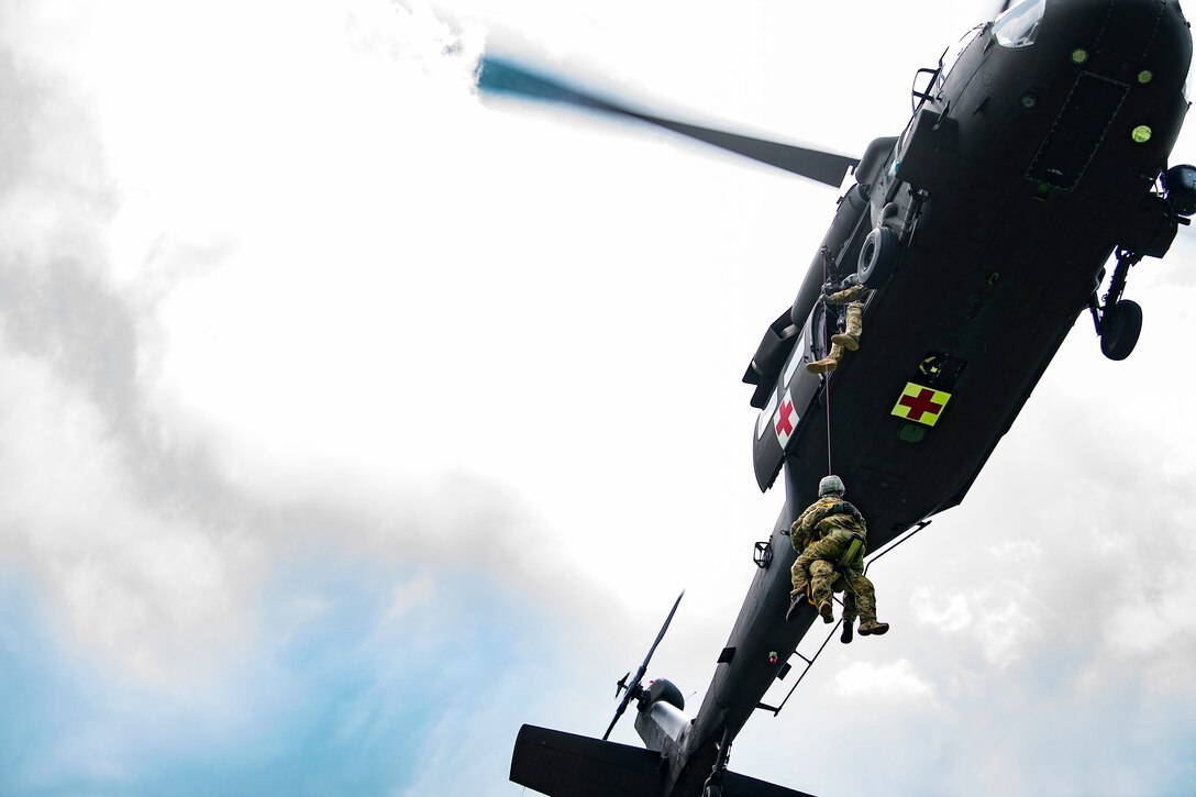 Soldiers hoist an airman into a UH-60 Black Hawk helicopter.