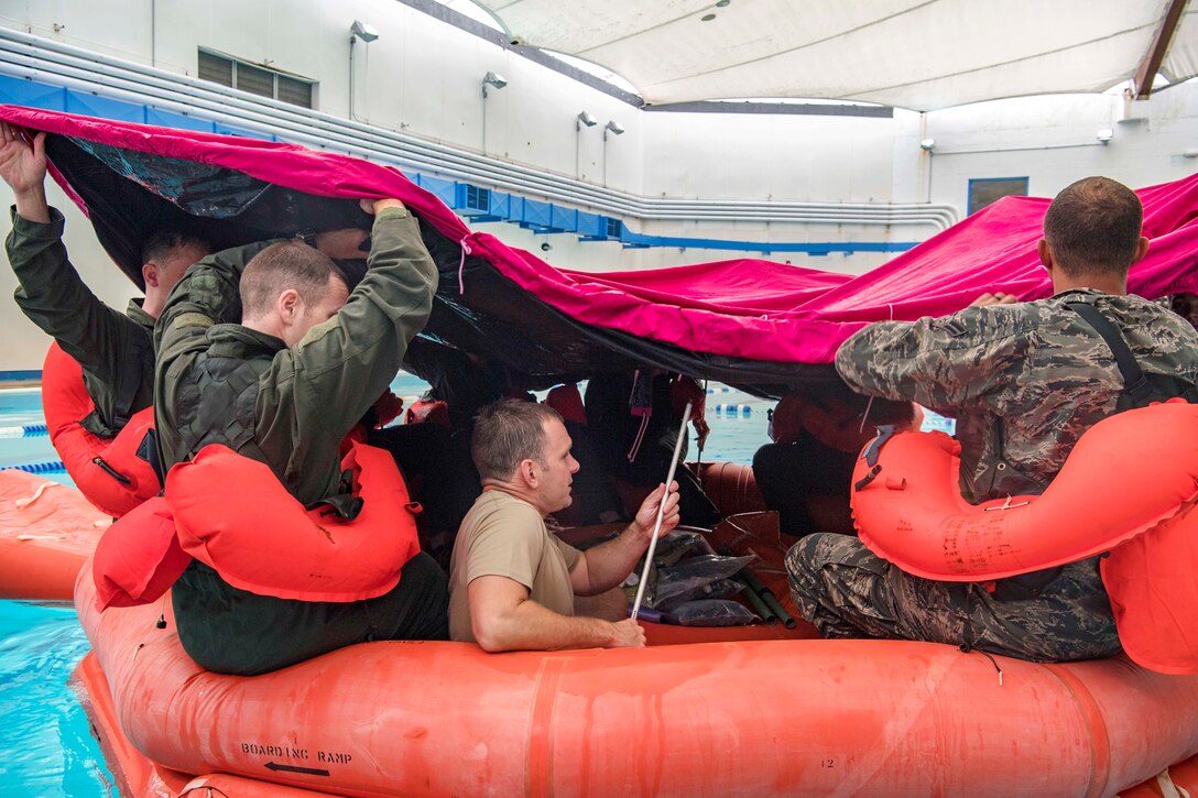 Airmen practice covering up in a rubber raft.