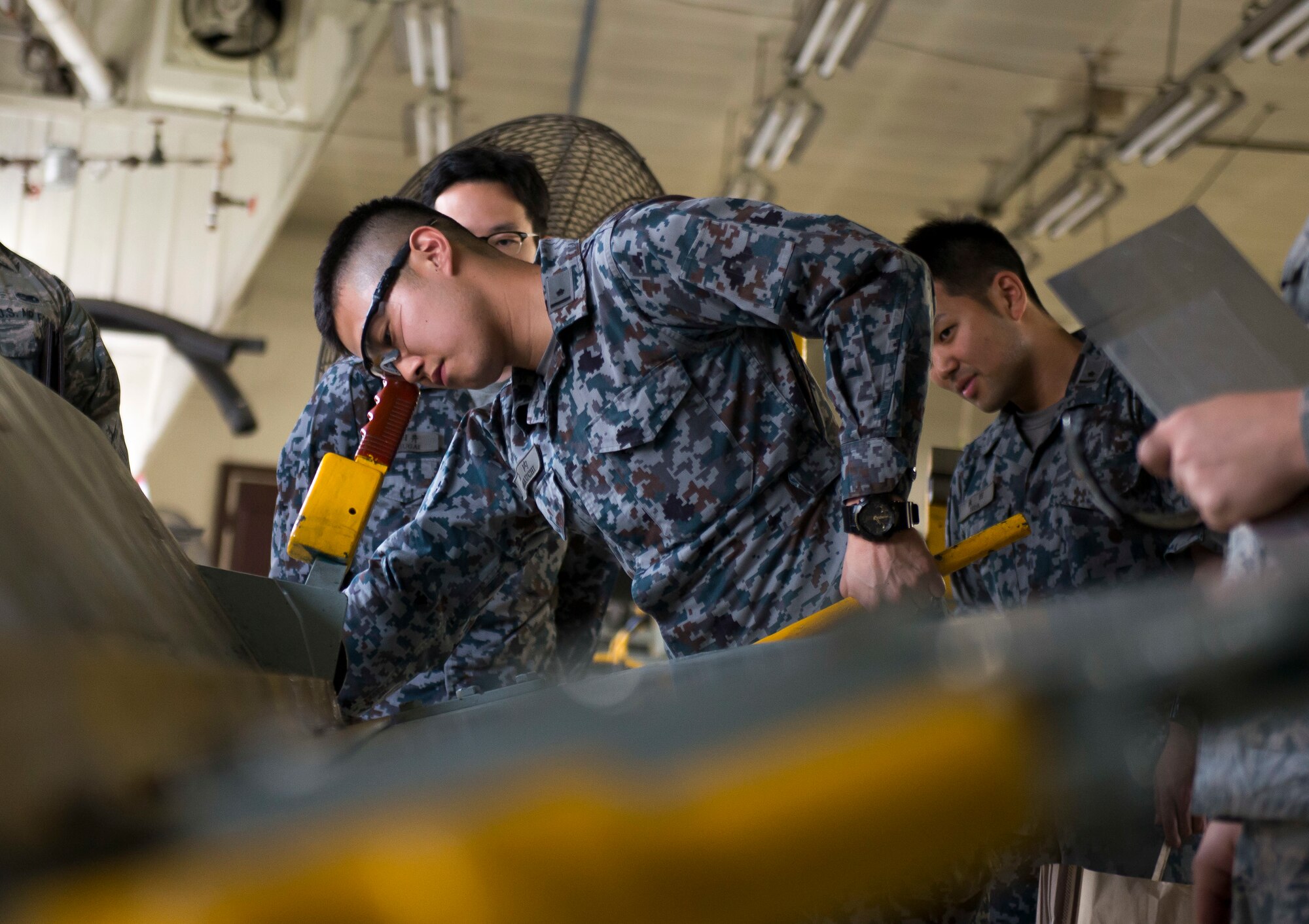 A Koku-Jieitai Maintenance officer bends a piece of sheet metal