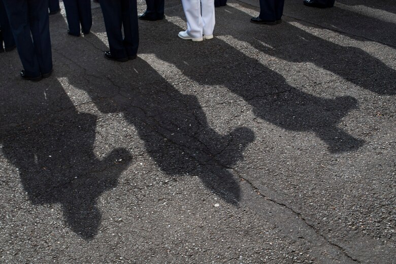 Service members salute during a ceremony for Memorial Day at Yokota Air Base