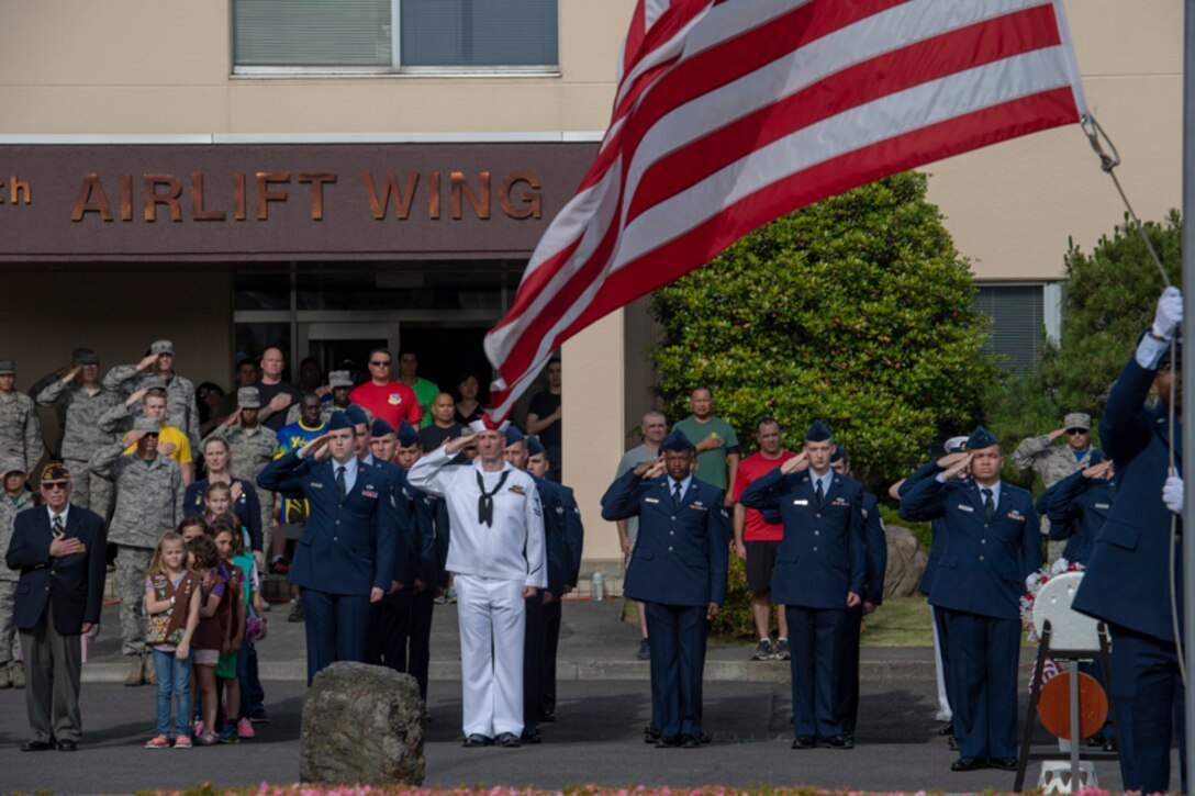 Service members salute during a ceremony for Memorial Day at Yokota Air Base