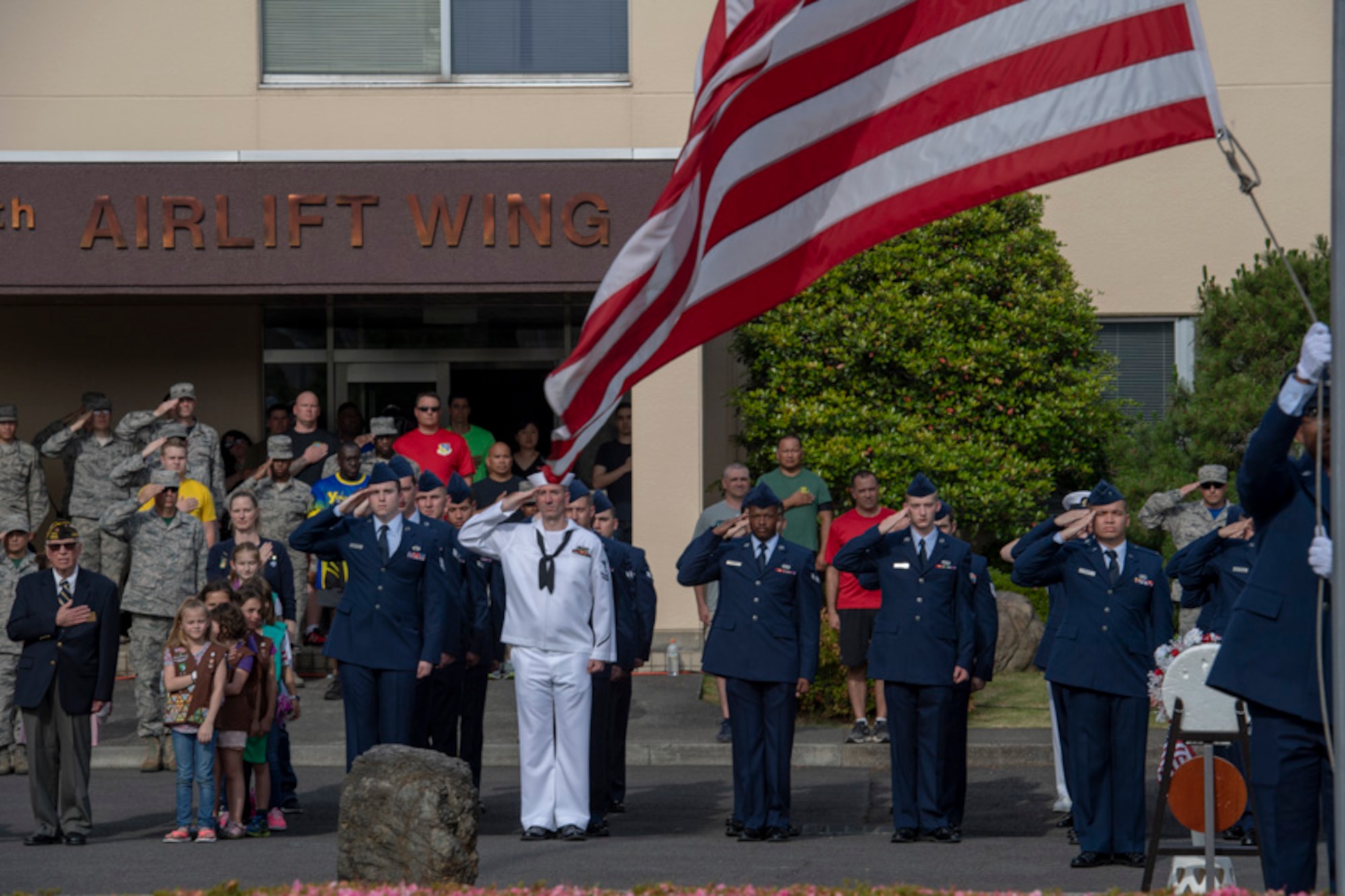 Service members salute during a ceremony for Memorial Day at Yokota Air Base