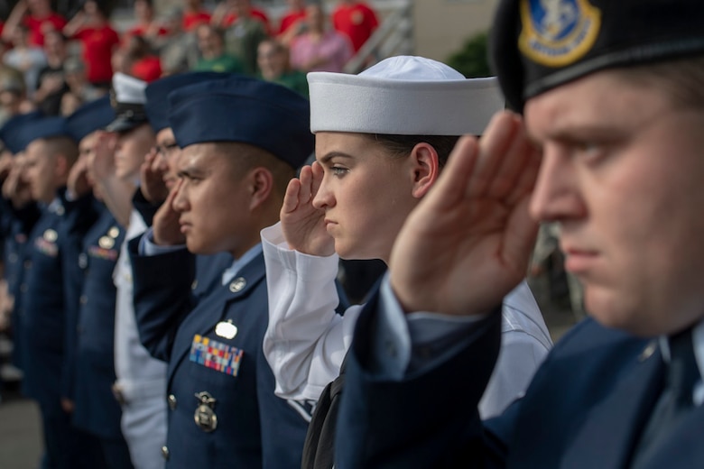 Service members salute during a ceremony for Memorial Day